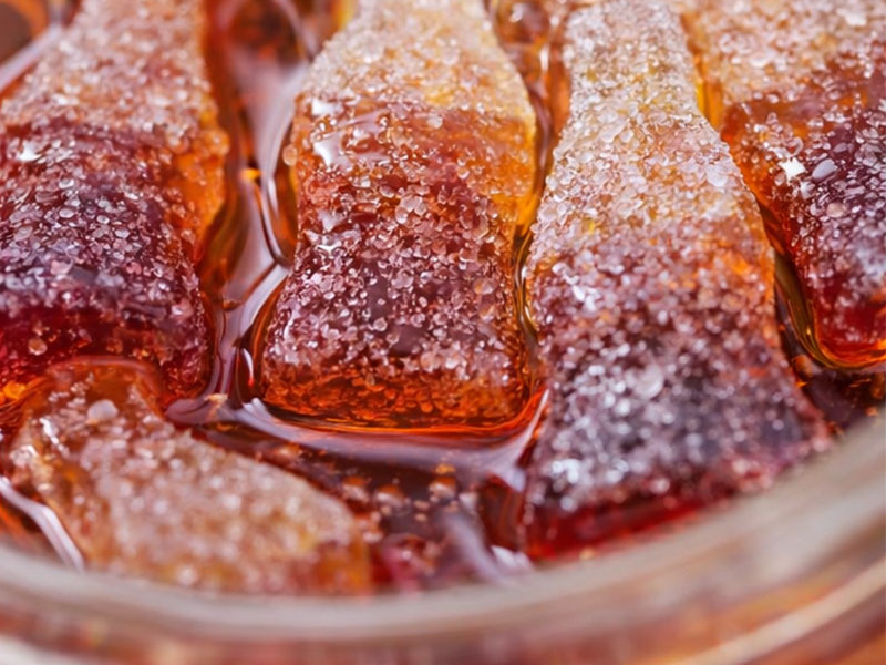 Caramelos gomosos pegajosos en un frasco transparente con gomitas de colores completamente sumergidas en almíbar líquido saborizado.